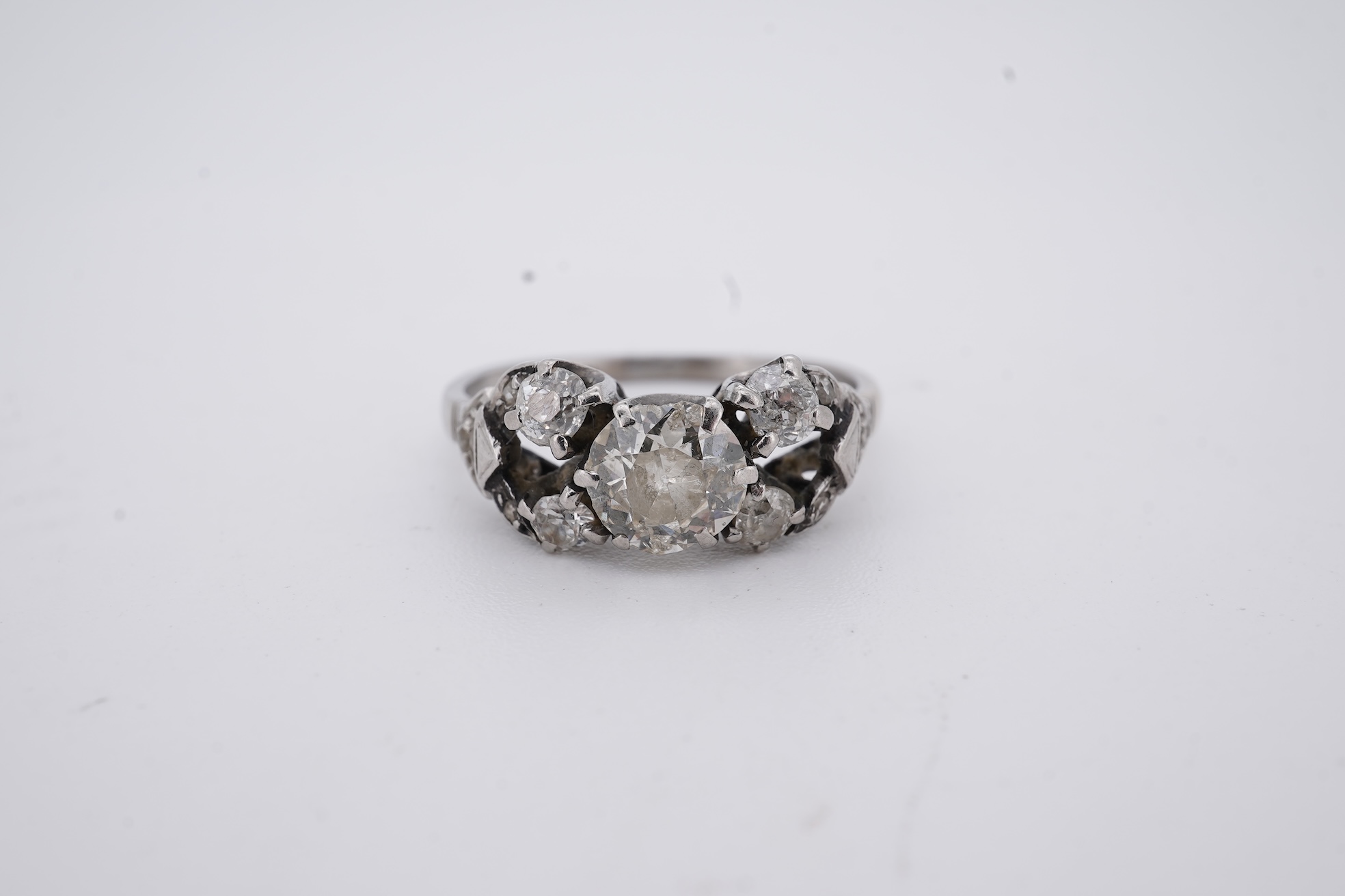 A white metal (stamped platin) and single stone diamond ring, flanked by four smaller diamonds and rose cut diamond chip set shoulders, size P, gross weight 3.8 grams.
